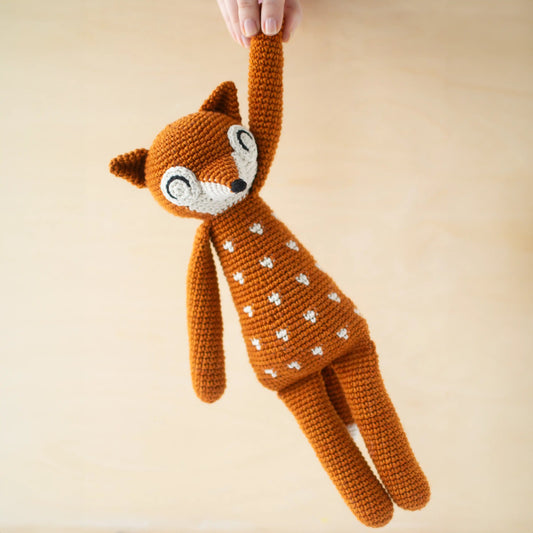 Crocheted orange amigurumi fox with white dots