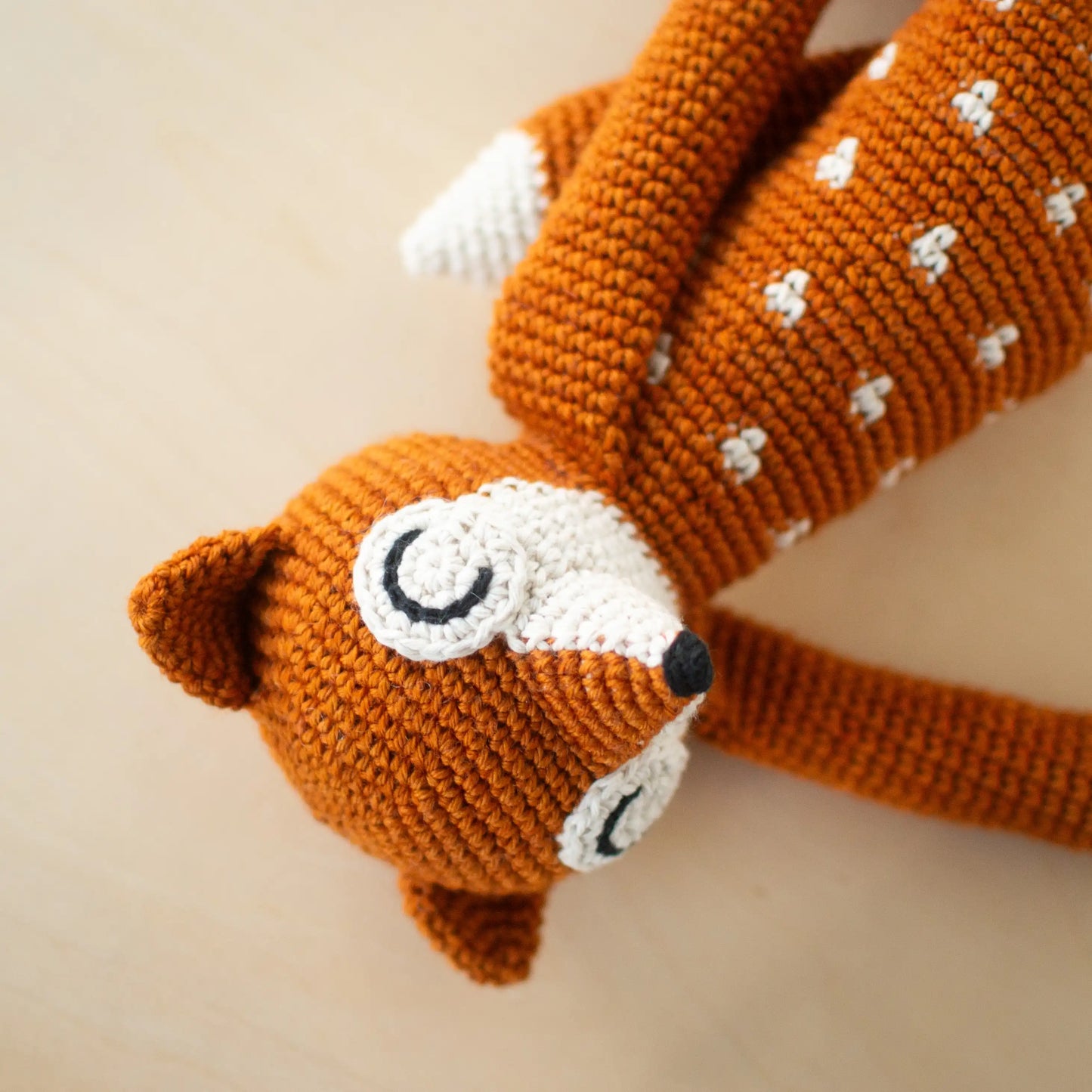 Crocheted orange amigurumi fox with white dots