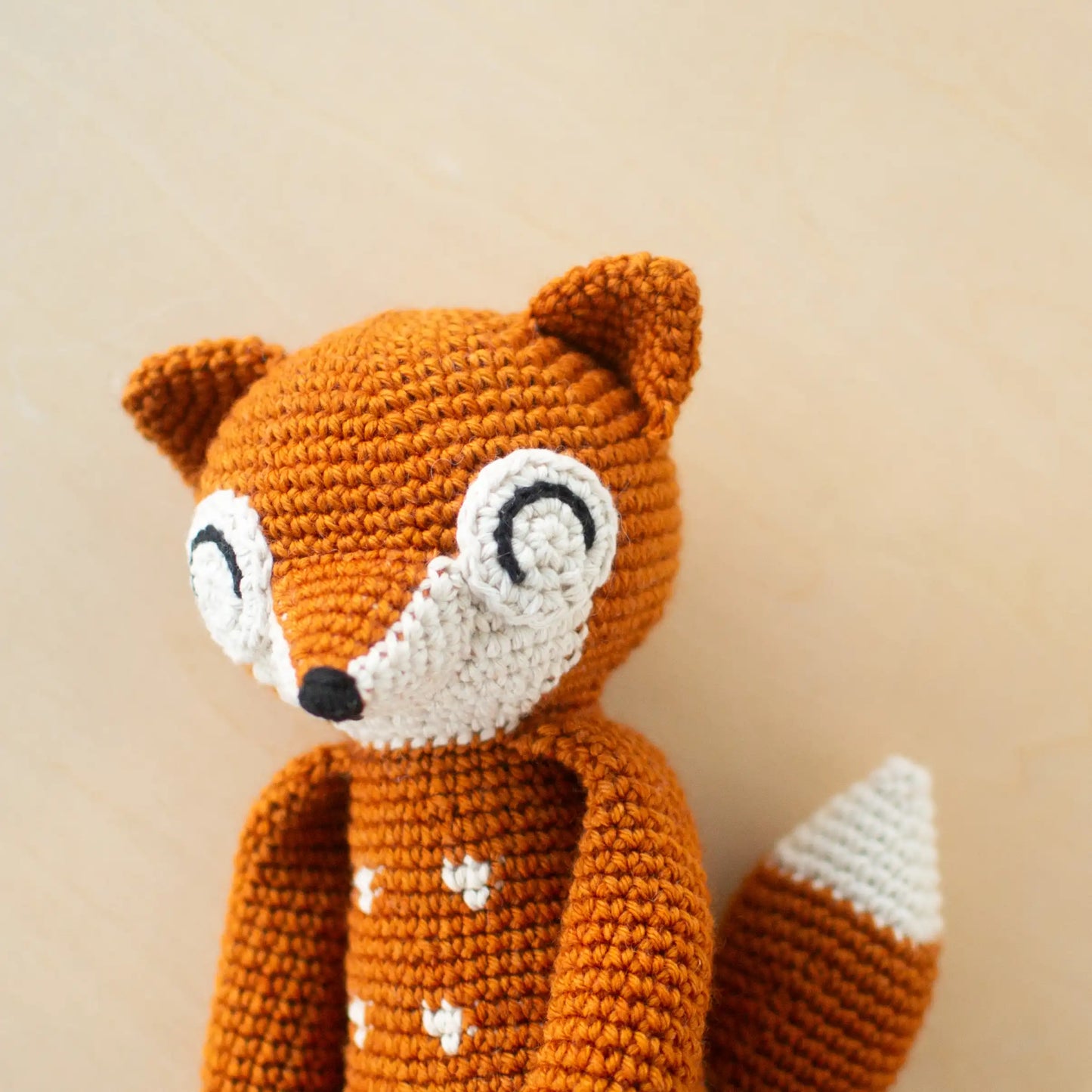 Crocheted orange amigurumi fox with white dots