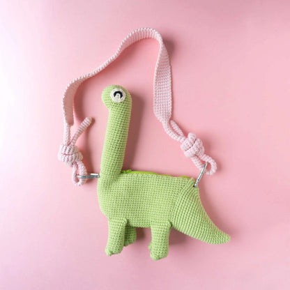 Crocheted brachiosaurus dinosaur bag on a pink background.