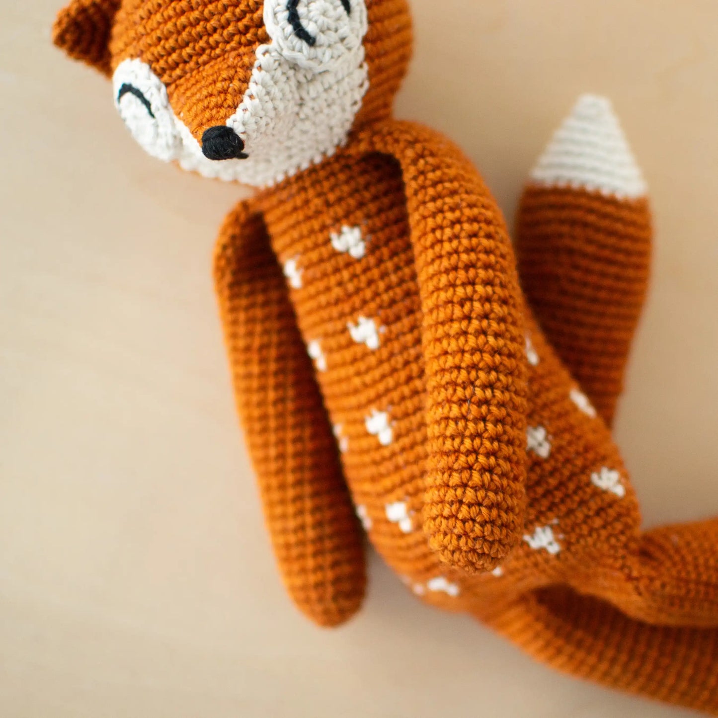 Crocheted orange amigurumi fox with white dots